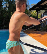 Load image into Gallery viewer, Man wearing sustainable mens swim briefs with avocado print by Salty Johnson AU by the pool