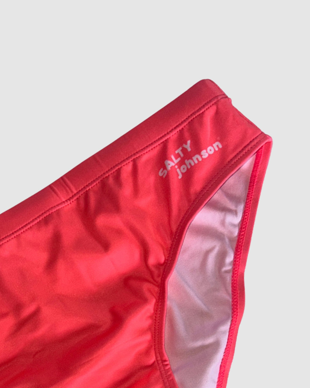 Waistband and front lining detail of Salty Johnson Classics Watermelon men's swim briefs in watermelon red.