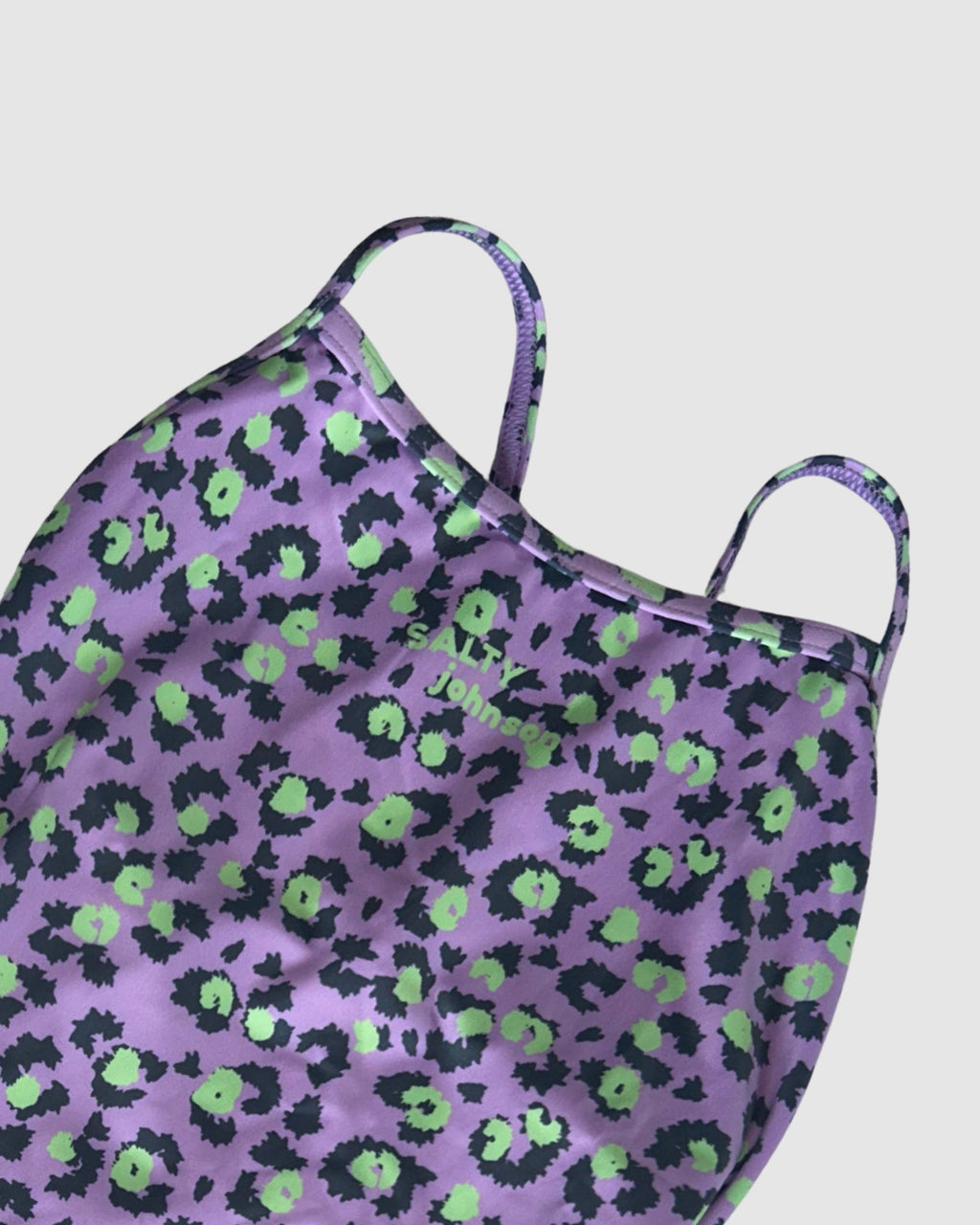Neckline and print detail of Purple Patch women's thin strap one-piece swimsuit, black and lime leopard spots on lilac.