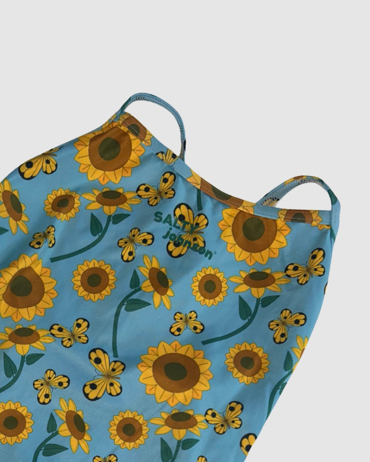 Neckline and print detail of Sunny Side Up women's thin strap one-piece swimsuit, yellow sunflowers on light blue.