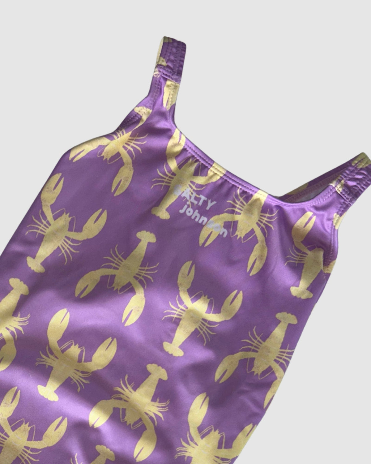 Neckline and print detail of Yabbies women's thick strap one-piece swimsuit, yellow yabby print on lilac.