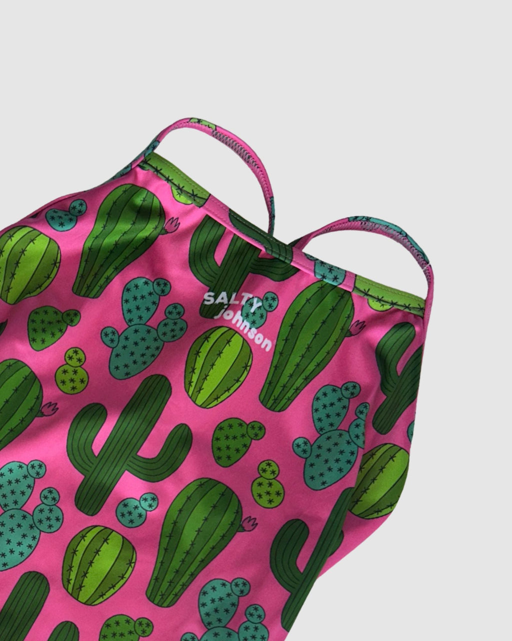 Neckline and print detail of Prickly Business Pink women's thin strap one-piece swimsuit, green cactus print on bright pink.