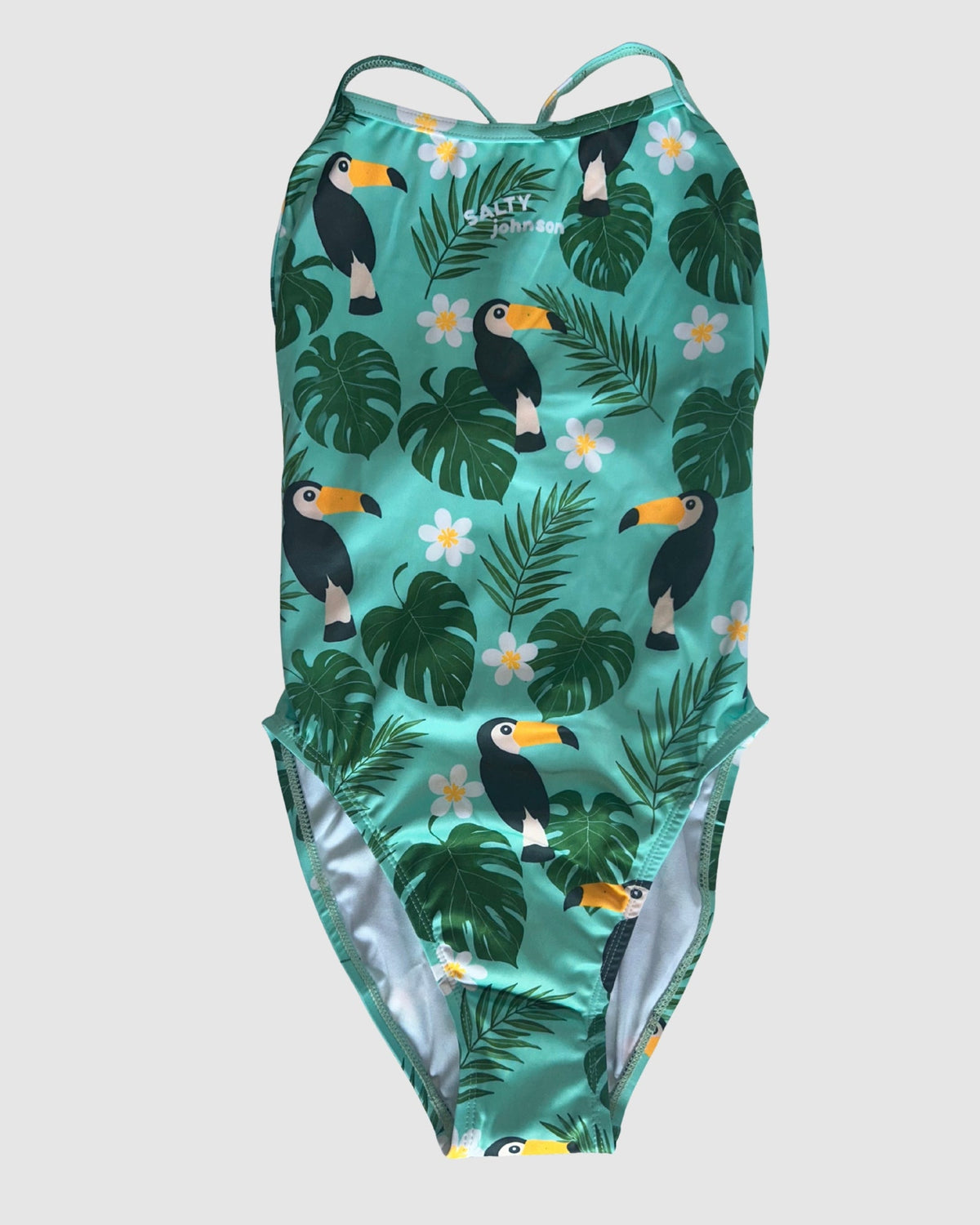 Front view of Toucan Tango women's thin strap one-piece swimsuit, toucans and tropical leaves on green.