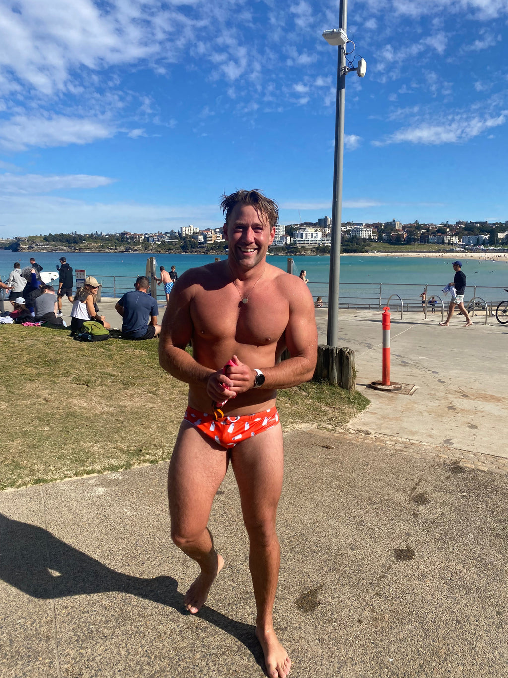 Man wearing sustainable mens swim briefs by Salty Johnson standing near the beach on a sunny day - Size 34